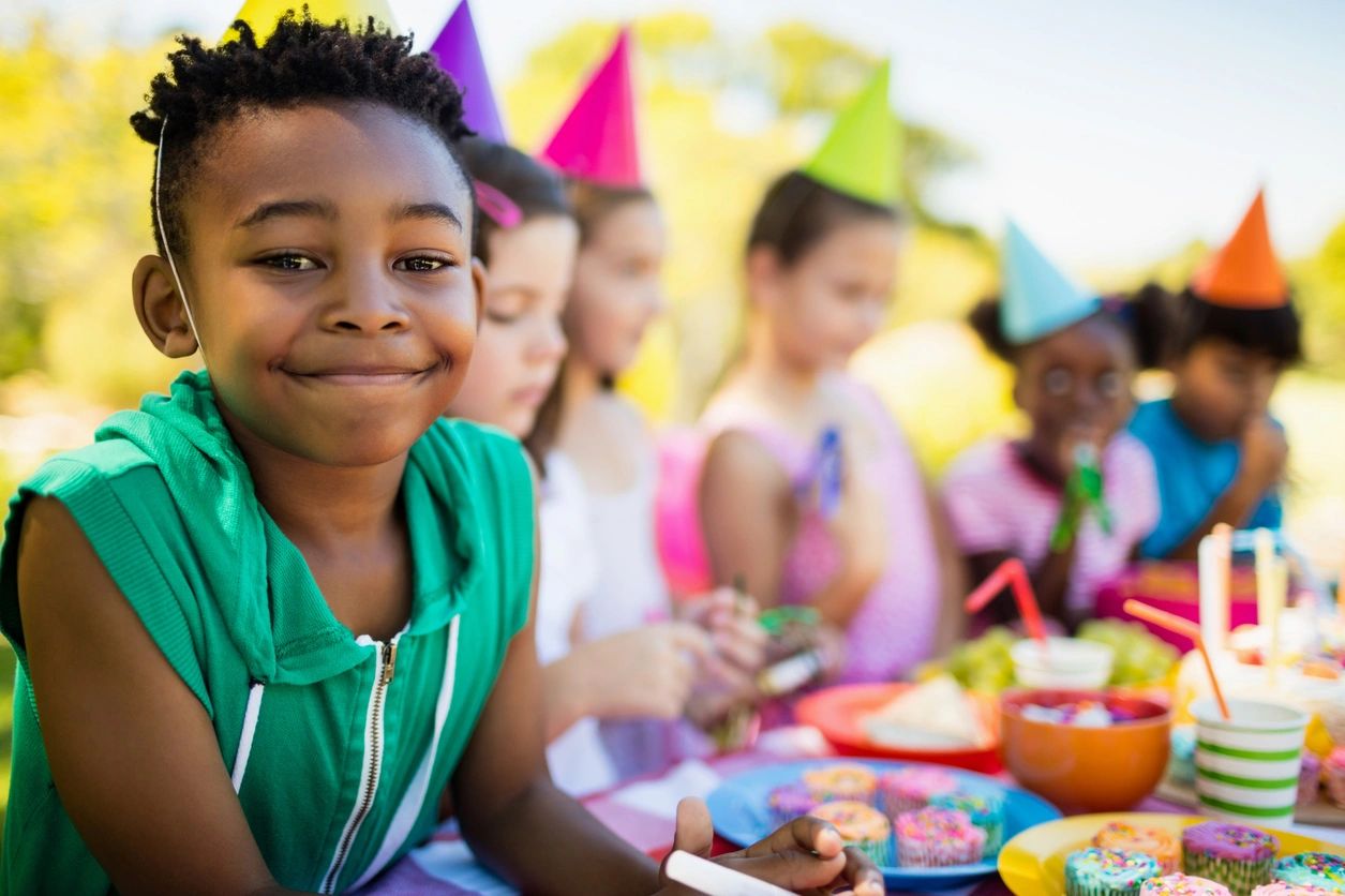 Child at colorful birthday party with hats and cupcakes