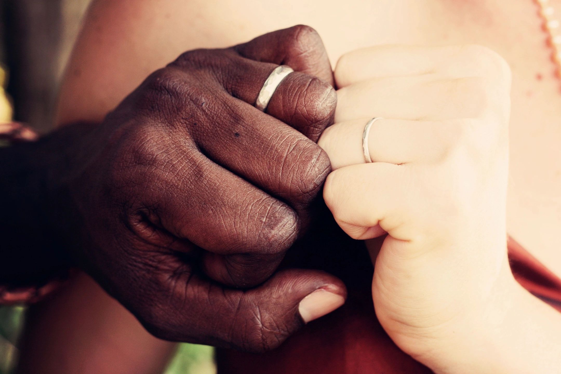 Hands clasped together wearing silver wedding rings